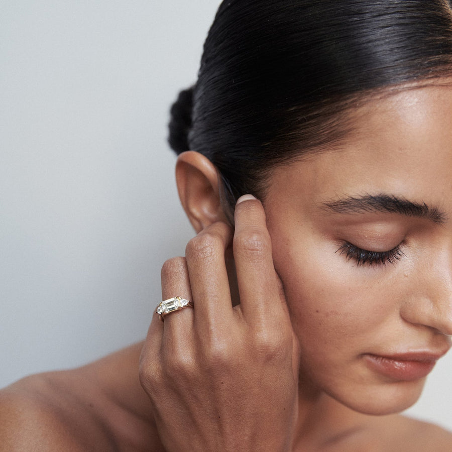 1.0 carat emerald cut lab grown diamond three stone engagement ring with side diamonds set on a polished gold band