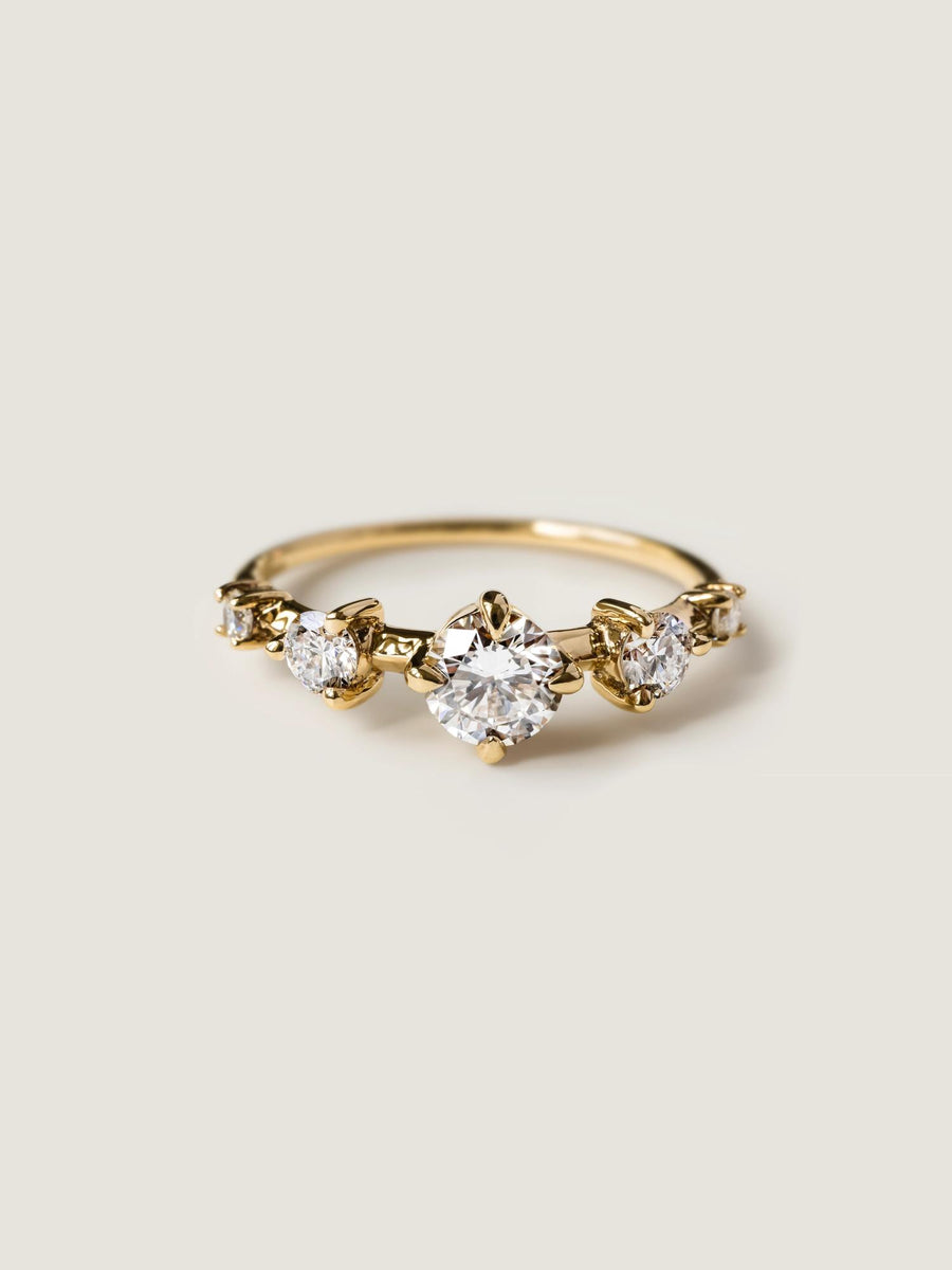 0.11 carat round cut lab grown diamond dainty engagement ring in a slim prong setting on polished gold band