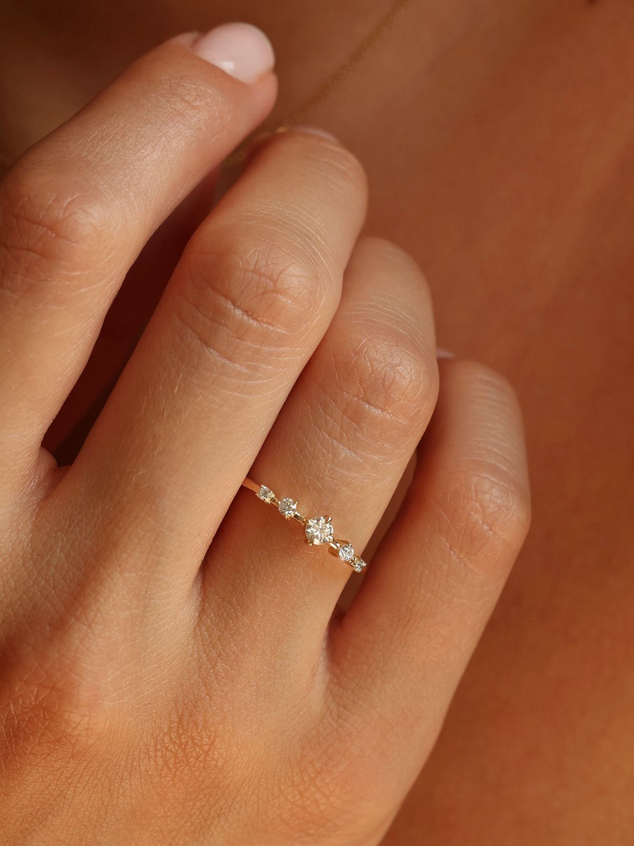 0.11 carat round cut lab grown diamond dainty engagement ring in E/VS1 clarity, set in a slim gold band with prong setting