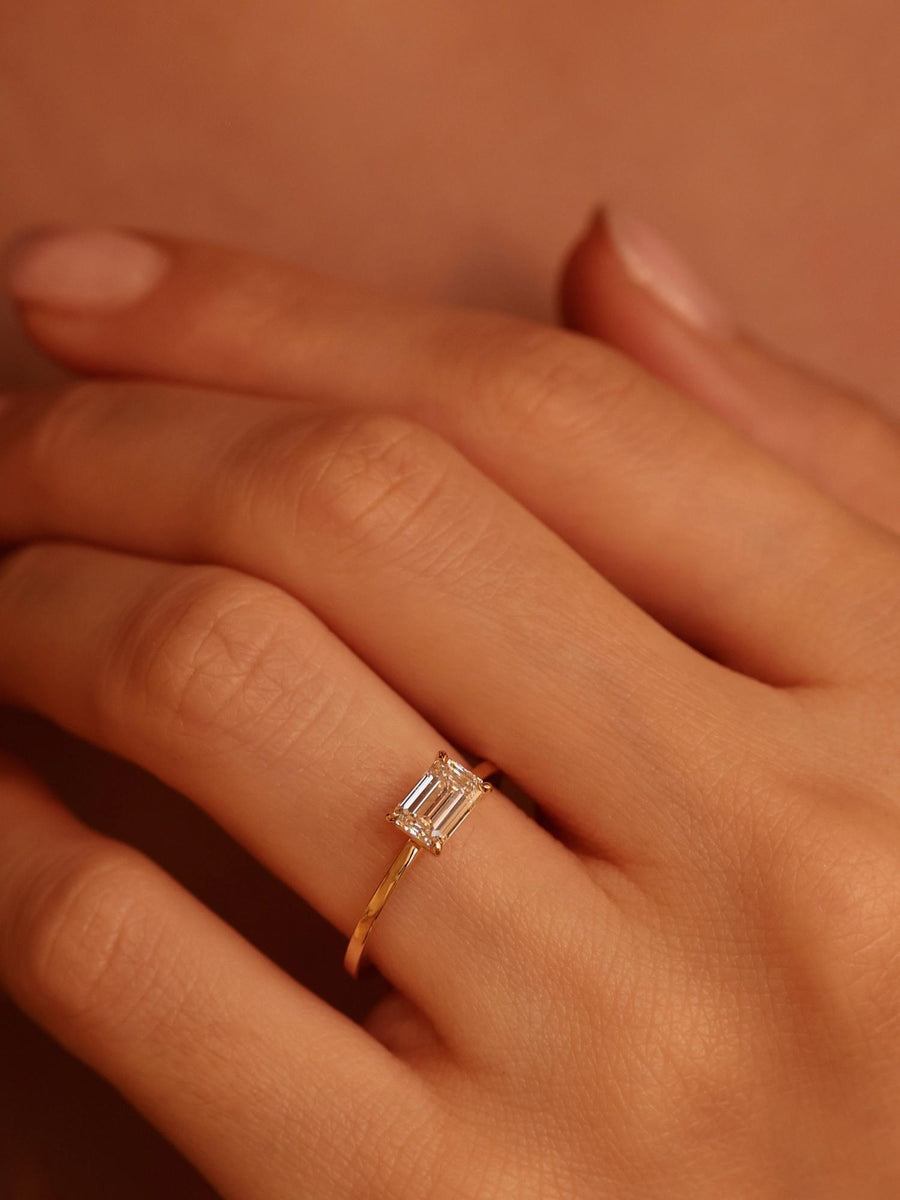 East-west emerald cut lab grown diamond solitaire engagement ring, 1.0 to 3.0 carats, set in prong design on polished gold band

