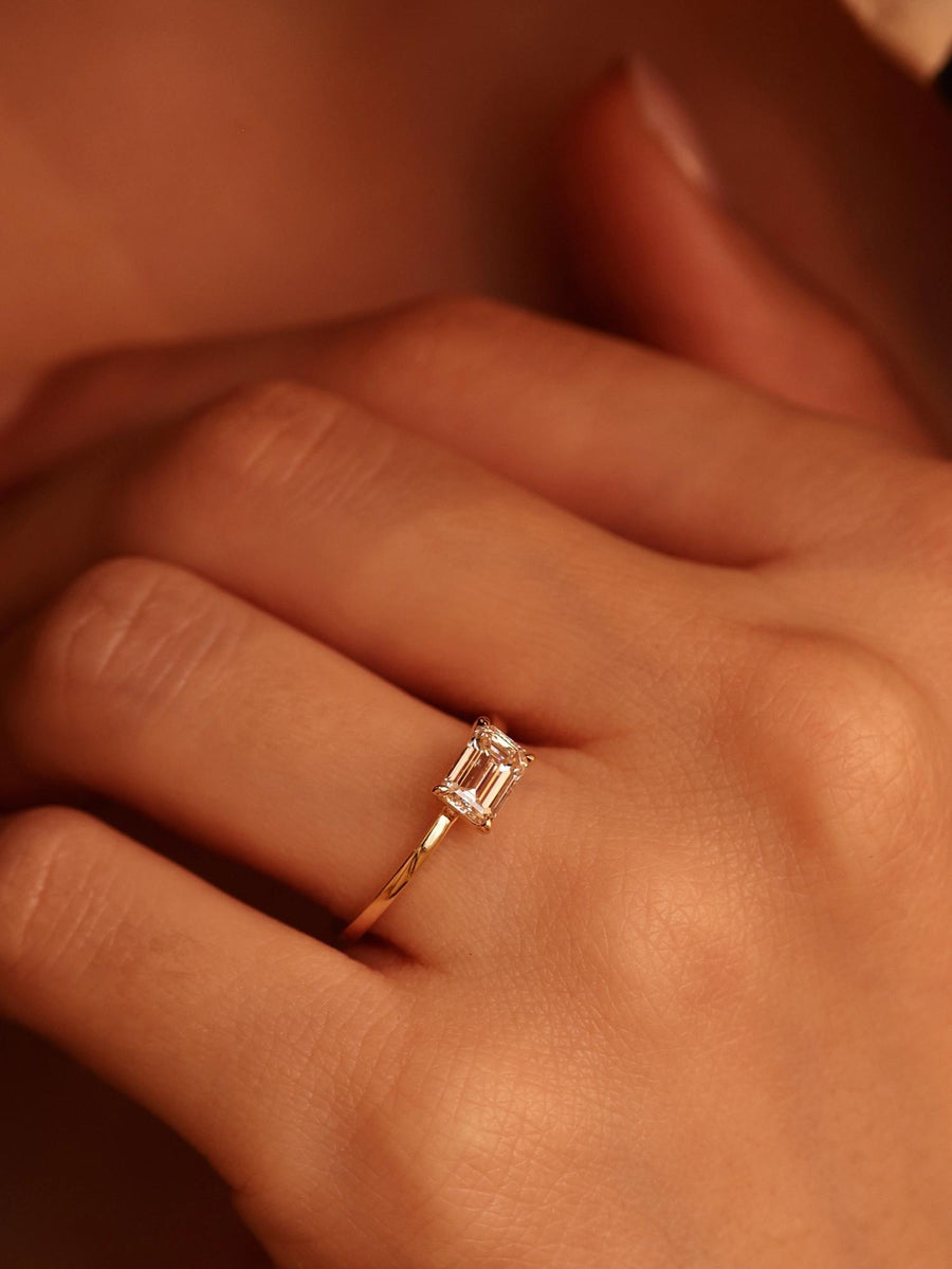 East-west emerald cut lab grown diamond solitaire engagement ring, 1.0 to 3.0 carats, set in prong design on polished gold band
