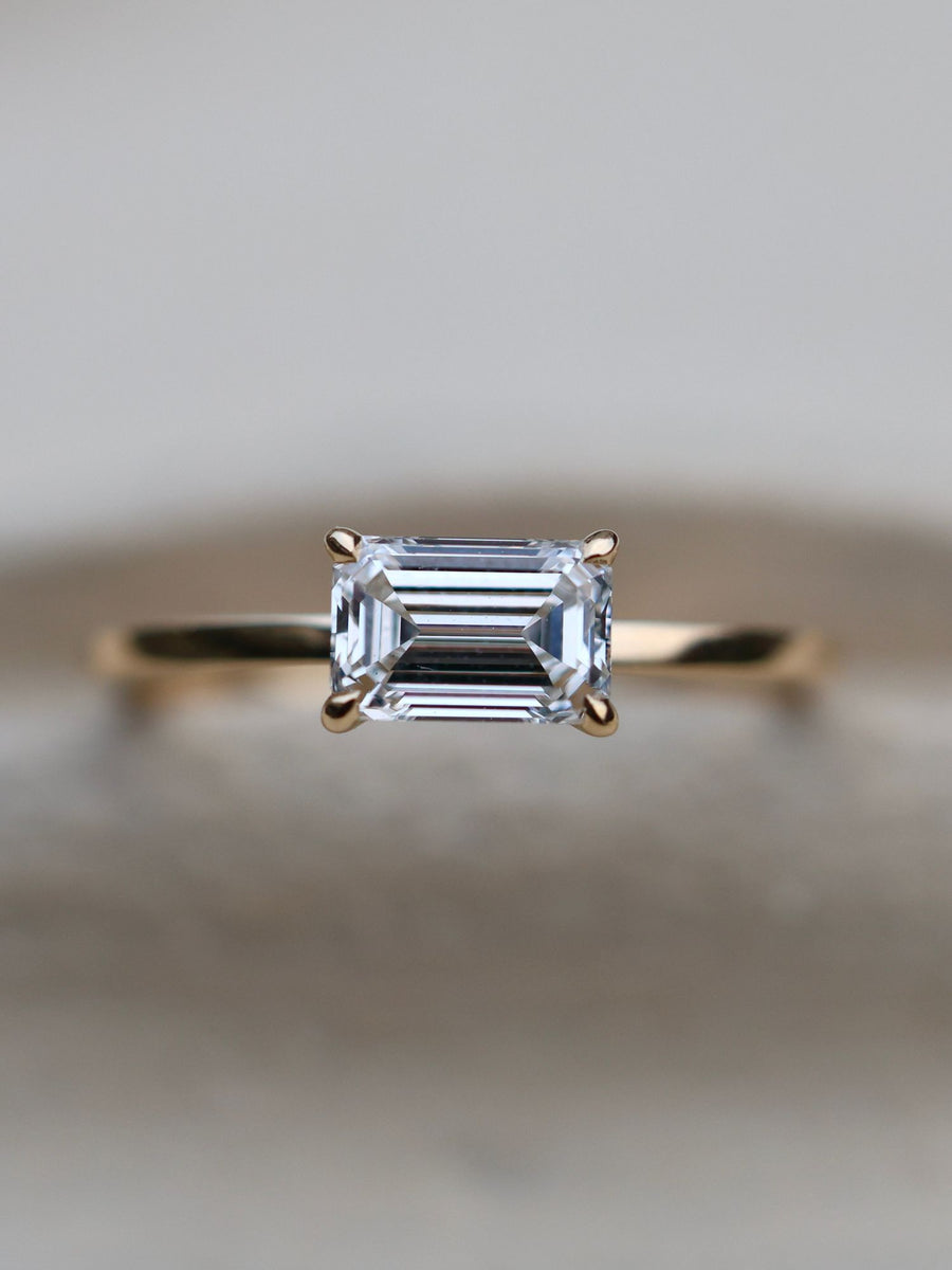 East-west emerald cut lab grown diamond solitaire engagement ring, 1.0 to 3.0 carats, set in prong design on polished gold band
