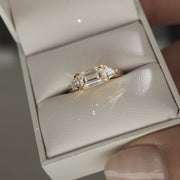 1.0 carat emerald cut lab grown diamond three stone engagement ring with side diamonds set on a polished gold band