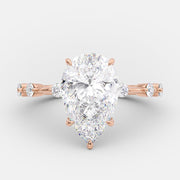 Pear cut lab grown diamond dainty pavé engagement ring with delicate side stones set in a slim prong setting on polished gold band