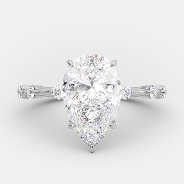 Pear cut lab grown diamond dainty pavé engagement ring with delicate side stones set in a slim prong setting on polished gold band
