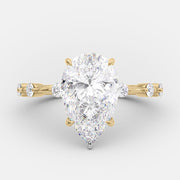 Pear cut lab grown diamond dainty pavé engagement ring with delicate side stones set in a slim prong setting on polished gold band