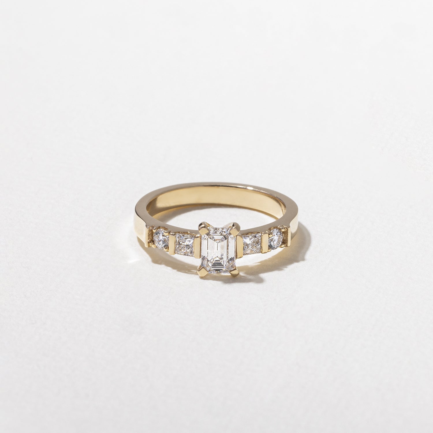 0.50 carat emerald cut lab grown diamond five stone engagement ring in prong setting on a polished gold band