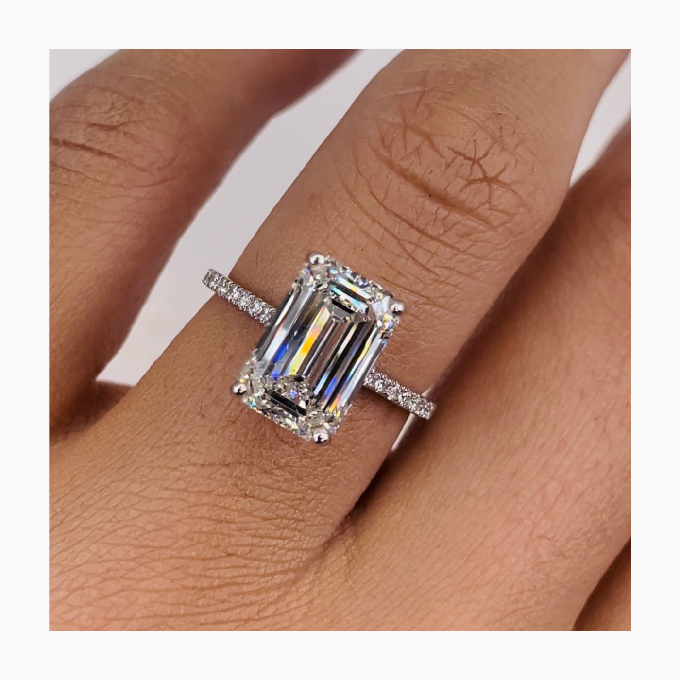 Emerald cut lab grown diamond pavé engagement ring with side stones set in a sleek prong setting on polished gold band