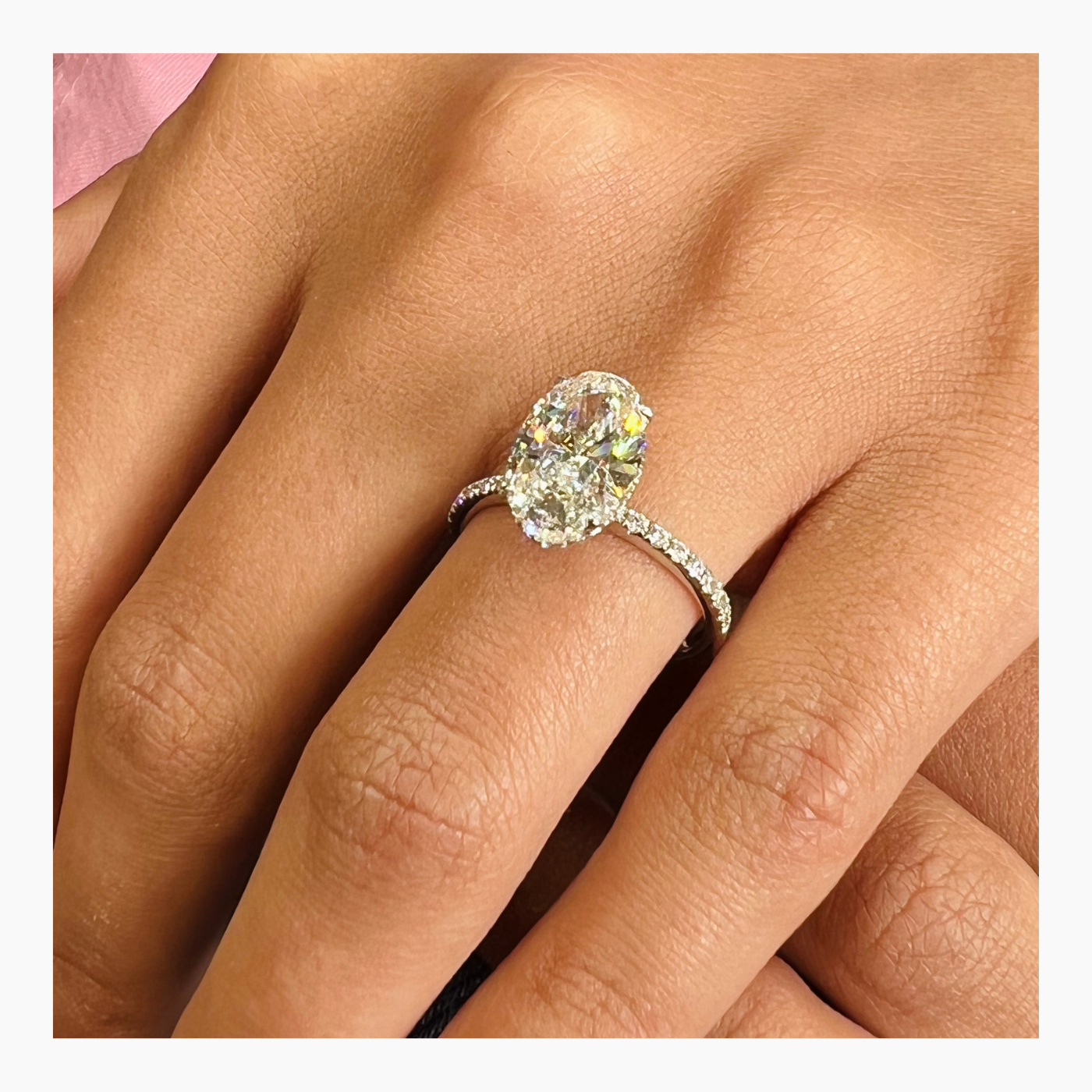 Oval cut lab grown diamond pavé engagement ring with sparkling side stones set along a polished gold band in elegant prong setting