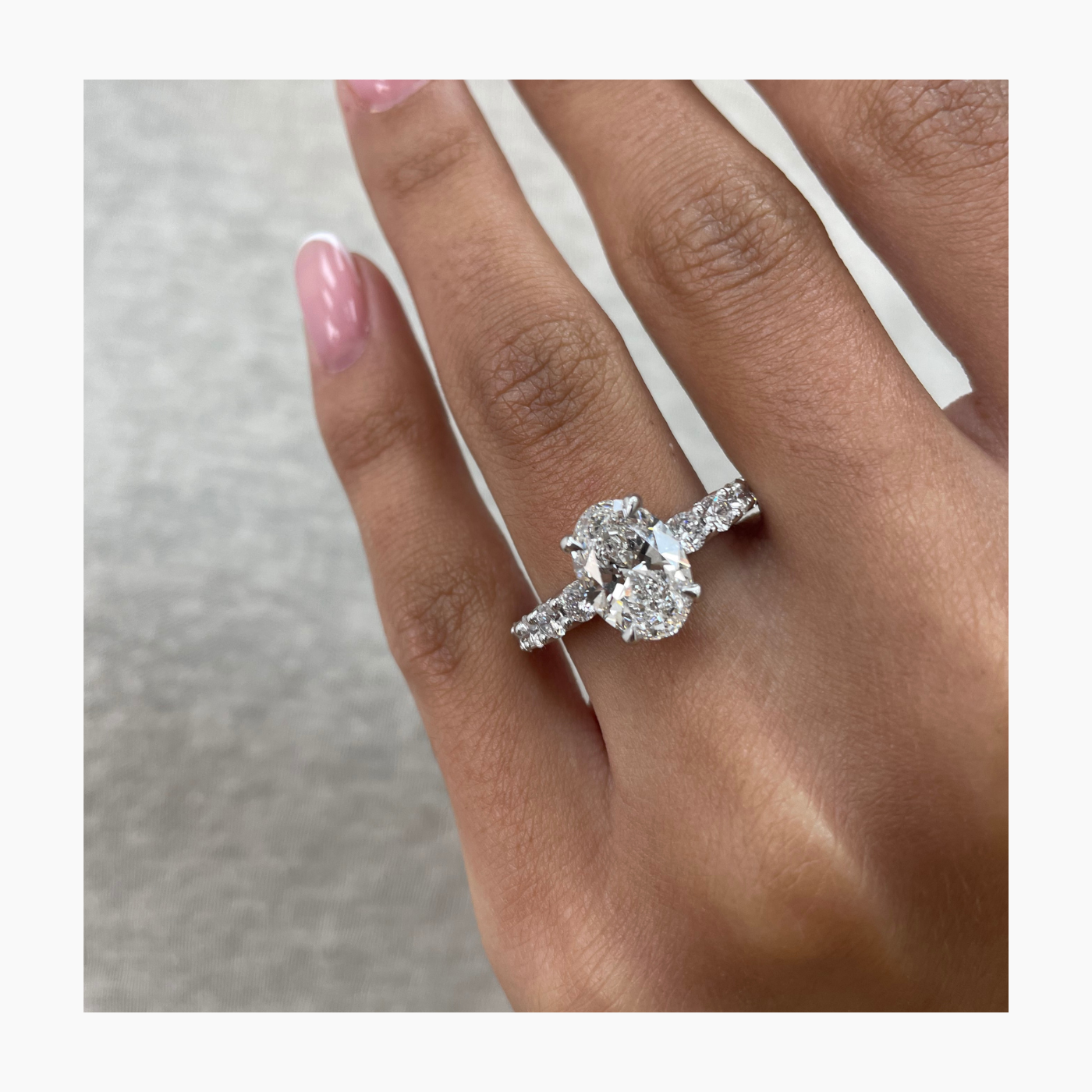 Oval cut lab grown diamond pavé setting engagement ring with side stones on polished gold band