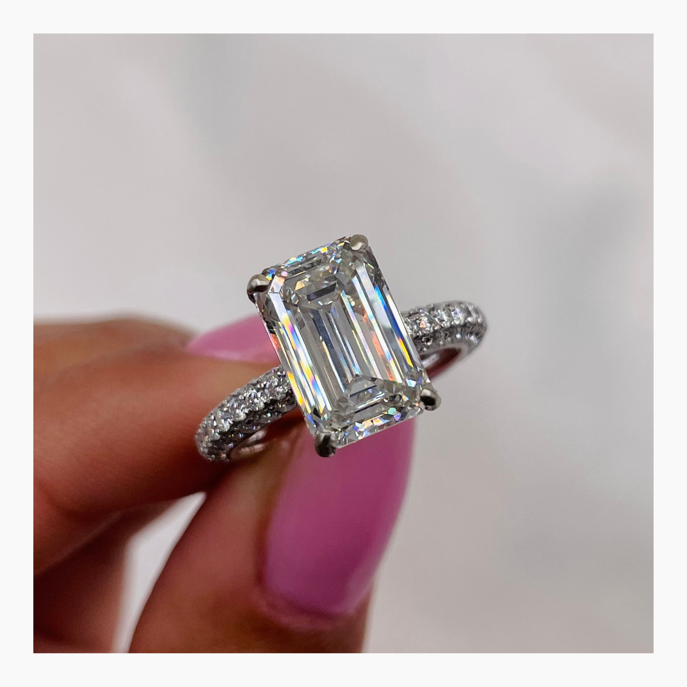 Emerald cut lab grown diamond pavé engagement ring with side stones in a classic prong setting on polished gold band