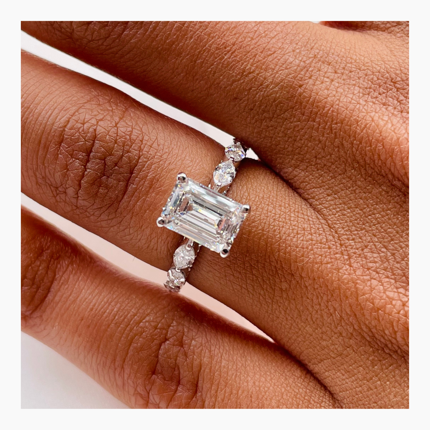 Emerald cut lab grown diamond engagement ring with pavé side stones set in a classic prong design on polished gold band