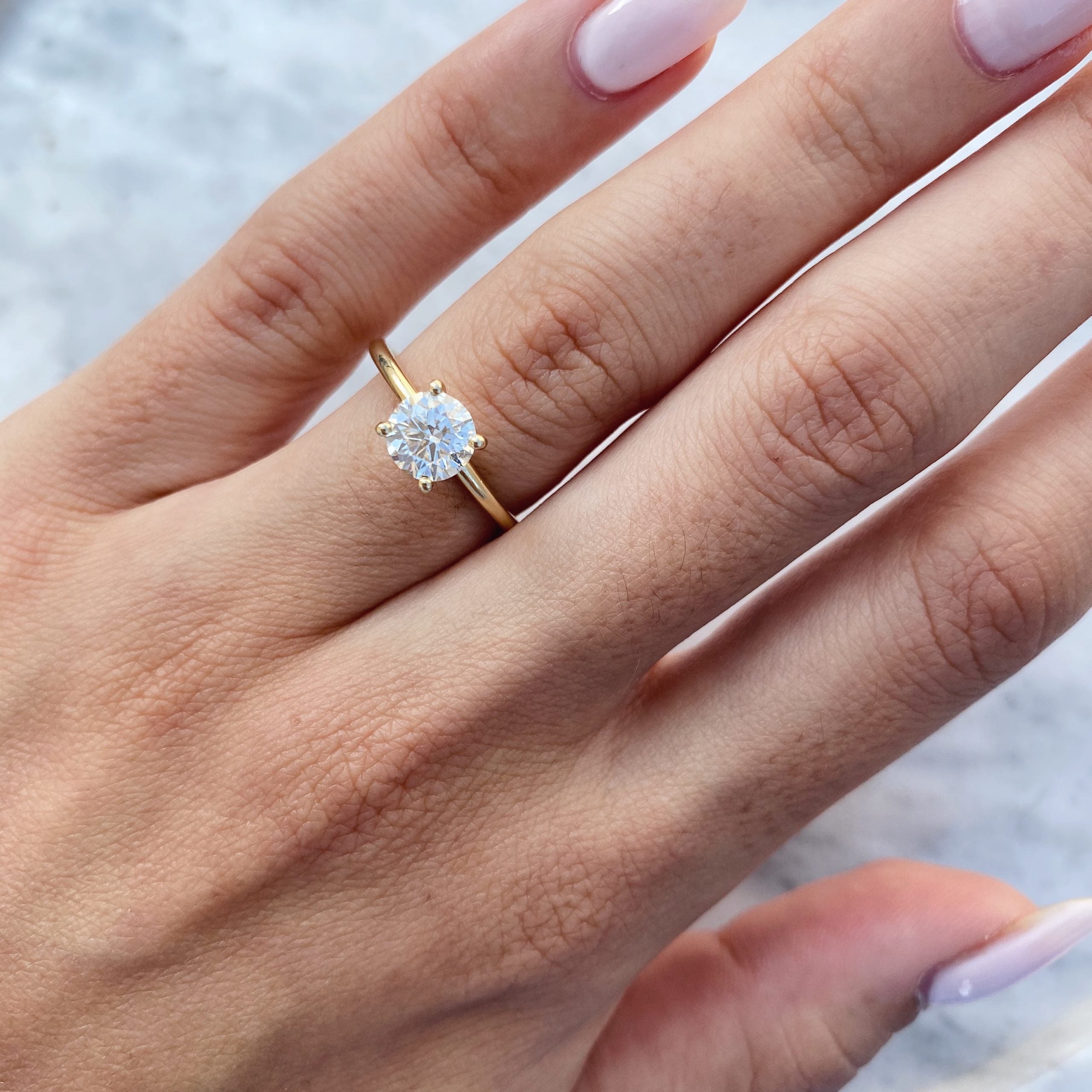 Round cut lab grown diamond hidden halo engagement ring with pavé accents set in polished gold band