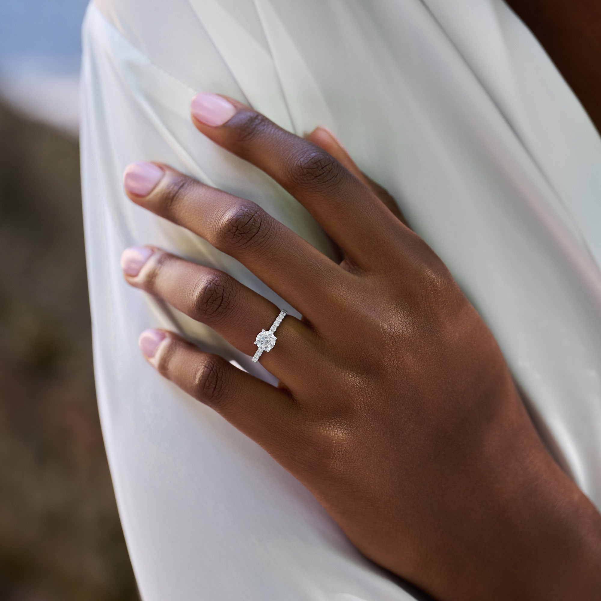 Round cut lab grown diamond pavé engagement ring with side stones in prong setting on a polished gold band