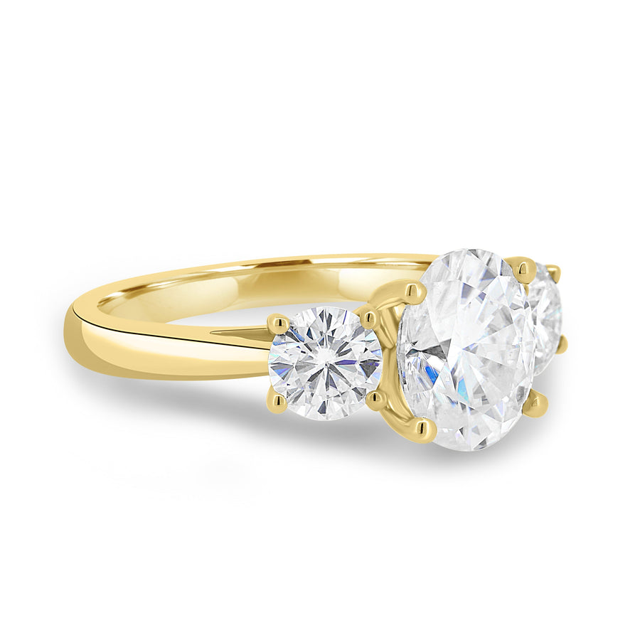 Oval cut lab grown diamond three stone engagement ring with center stone and side diamonds in classic prong setting on gold band