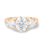 Oval cut lab grown diamond three stone engagement ring with center stone and side diamonds in classic prong setting on gold band
