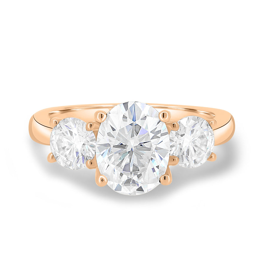 Oval cut lab grown diamond three stone engagement ring with center stone and side diamonds in classic prong setting on gold band