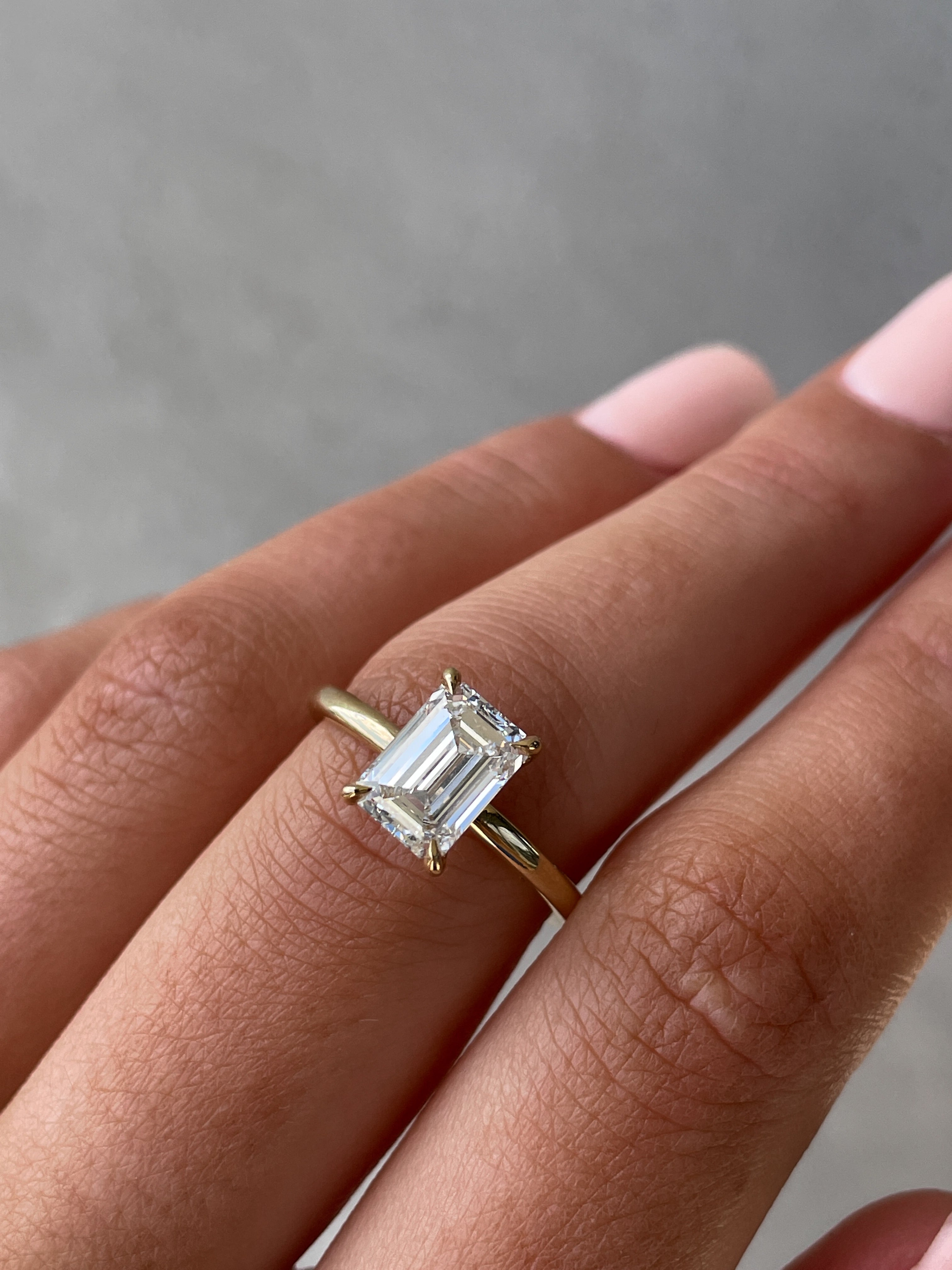 Emerald cut lab grown diamond engagement ring with hidden halo setting, crafted in polished gold band for elegant sparkle