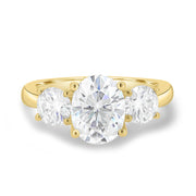 Oval cut lab grown diamond three stone engagement ring with center stone and side diamonds in classic prong setting on gold band