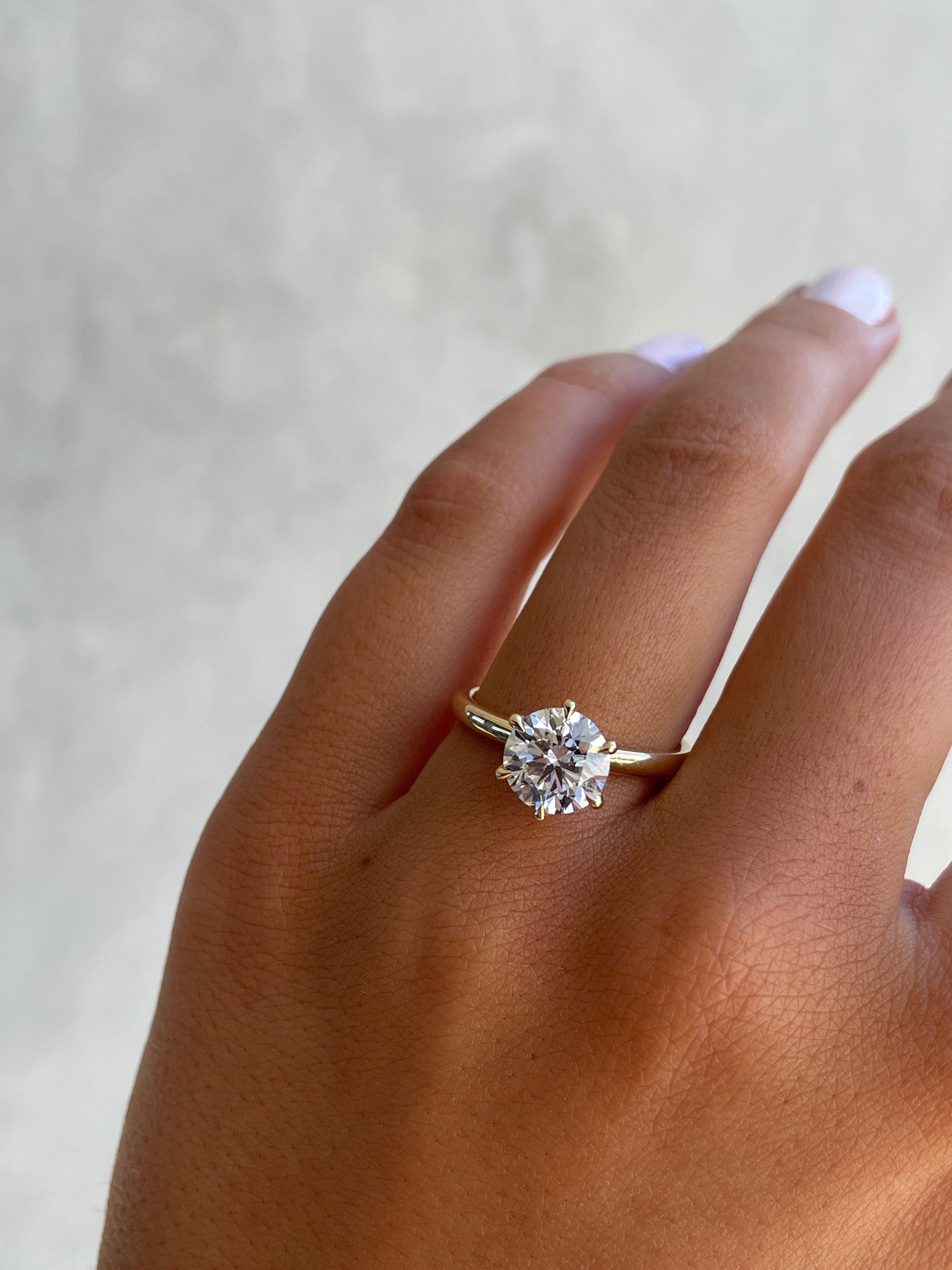 Round cut lab grown diamond solitaire engagement ring in classic prong setting on polished gold band