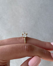 Oval cut lab grown diamond three stone engagement ring with center stone and side diamonds in classic prong setting on gold band