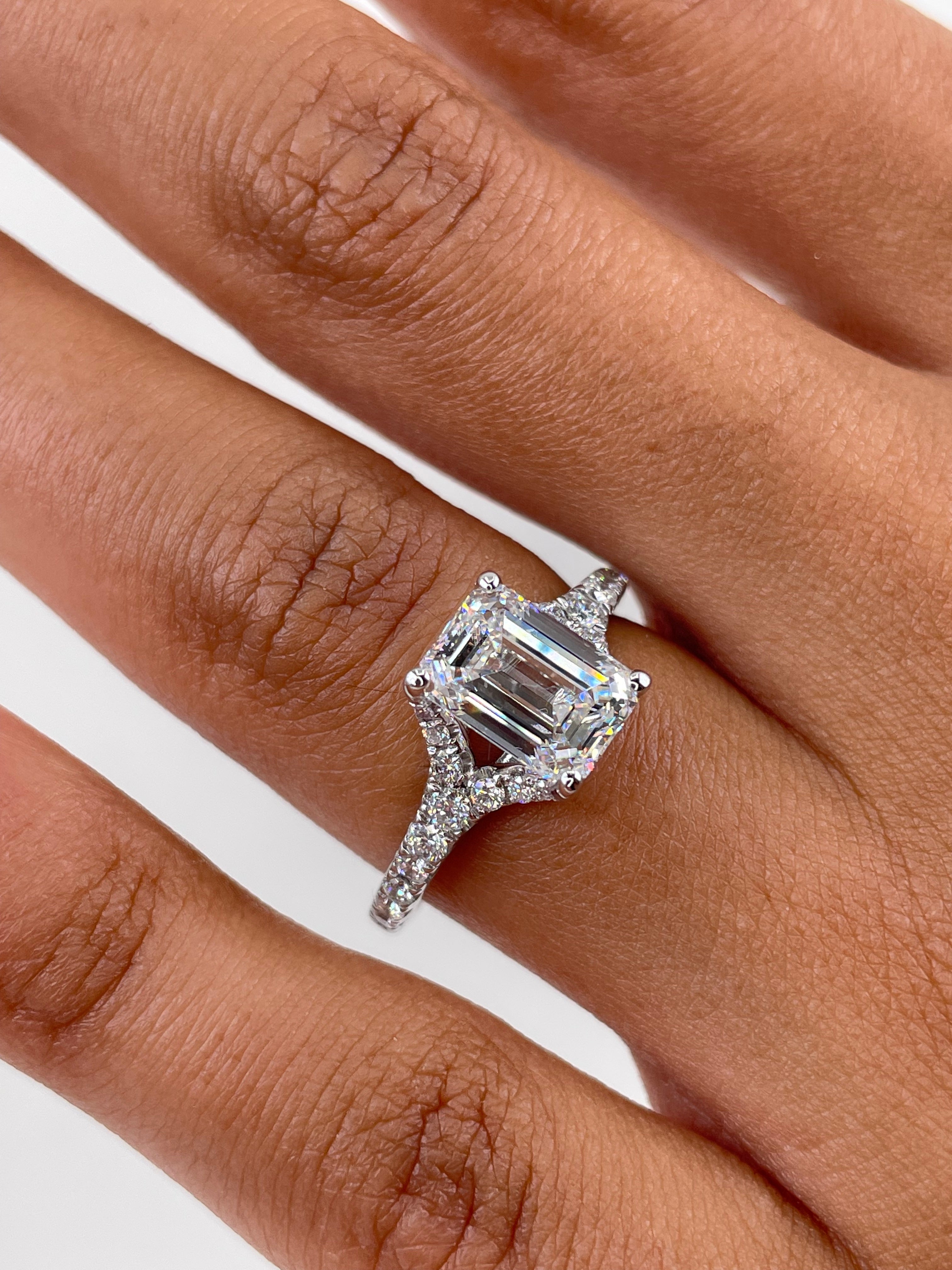 Emerald cut lab grown diamond engagement ring with pavé setting and side stones on a polished gold band