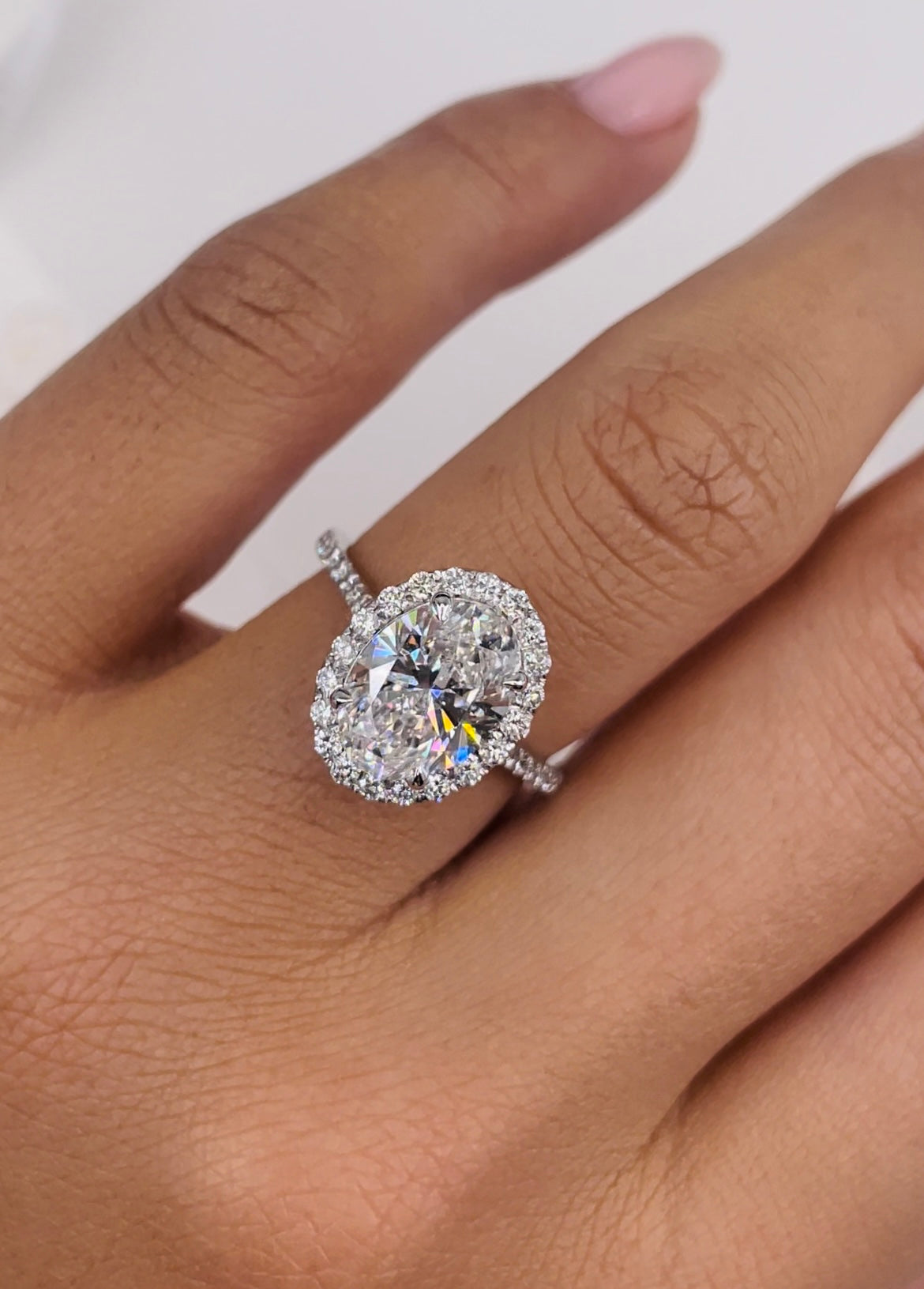 Oval cut lab grown diamond halo and pavé engagement ring with sparkling side stones set in polished gold band