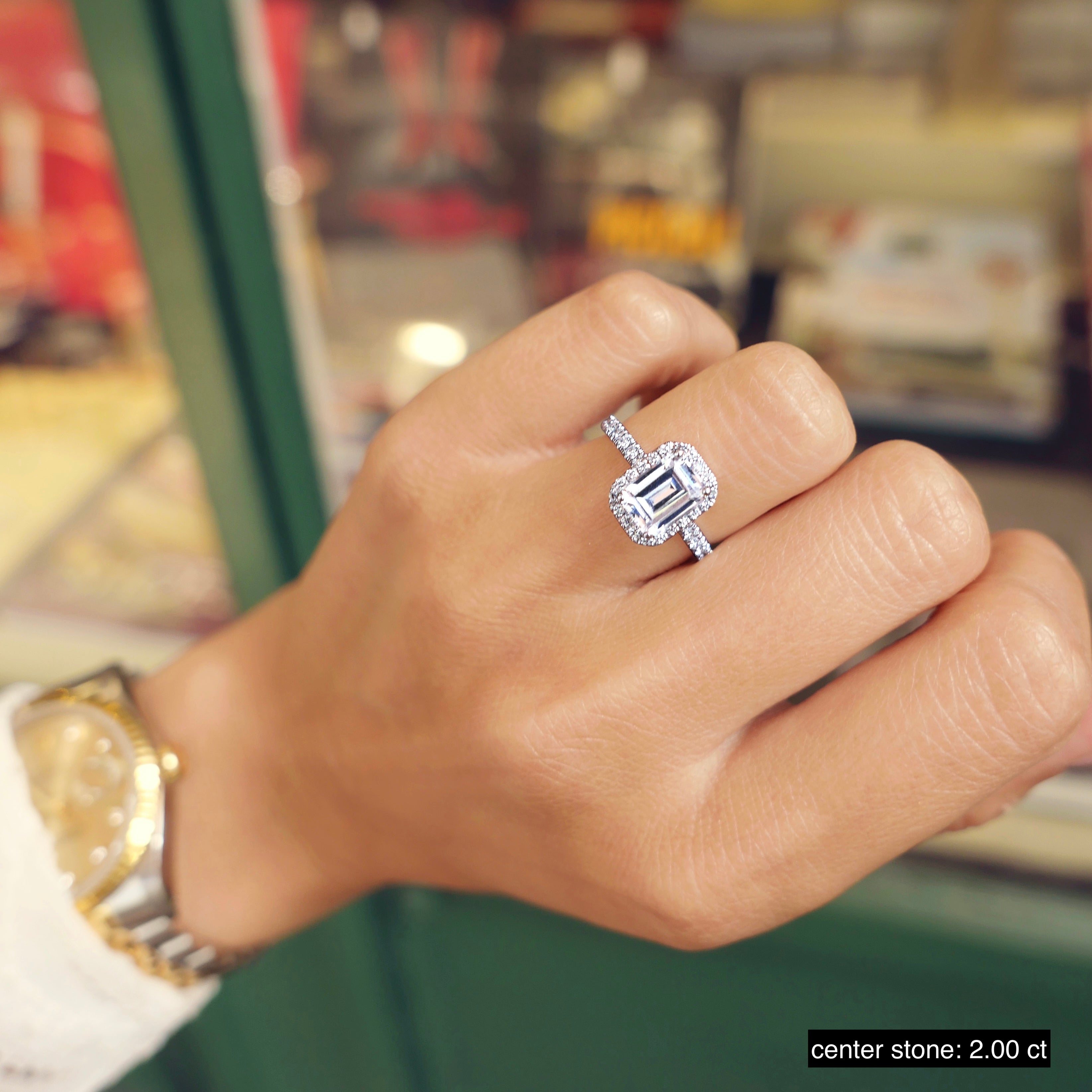 Emerald cut lab grown diamond halo and pavé engagement ring with side stones set on polished gold band