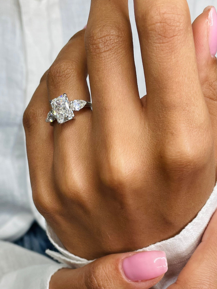 Three stone radiant cut lab grown diamond engagement ring with prong settings on polished gold band, showcasing elegant sparkle