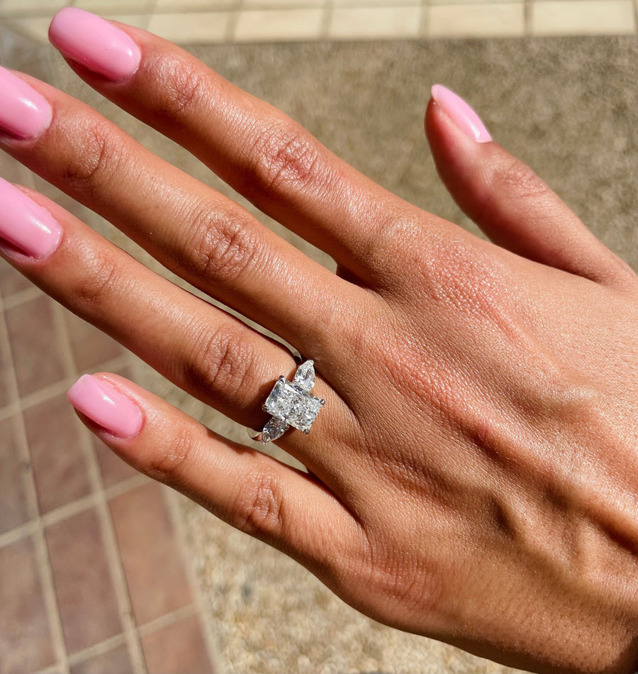 Three stone radiant cut lab grown diamond engagement ring with prong settings on polished gold band, showcasing elegant sparkle