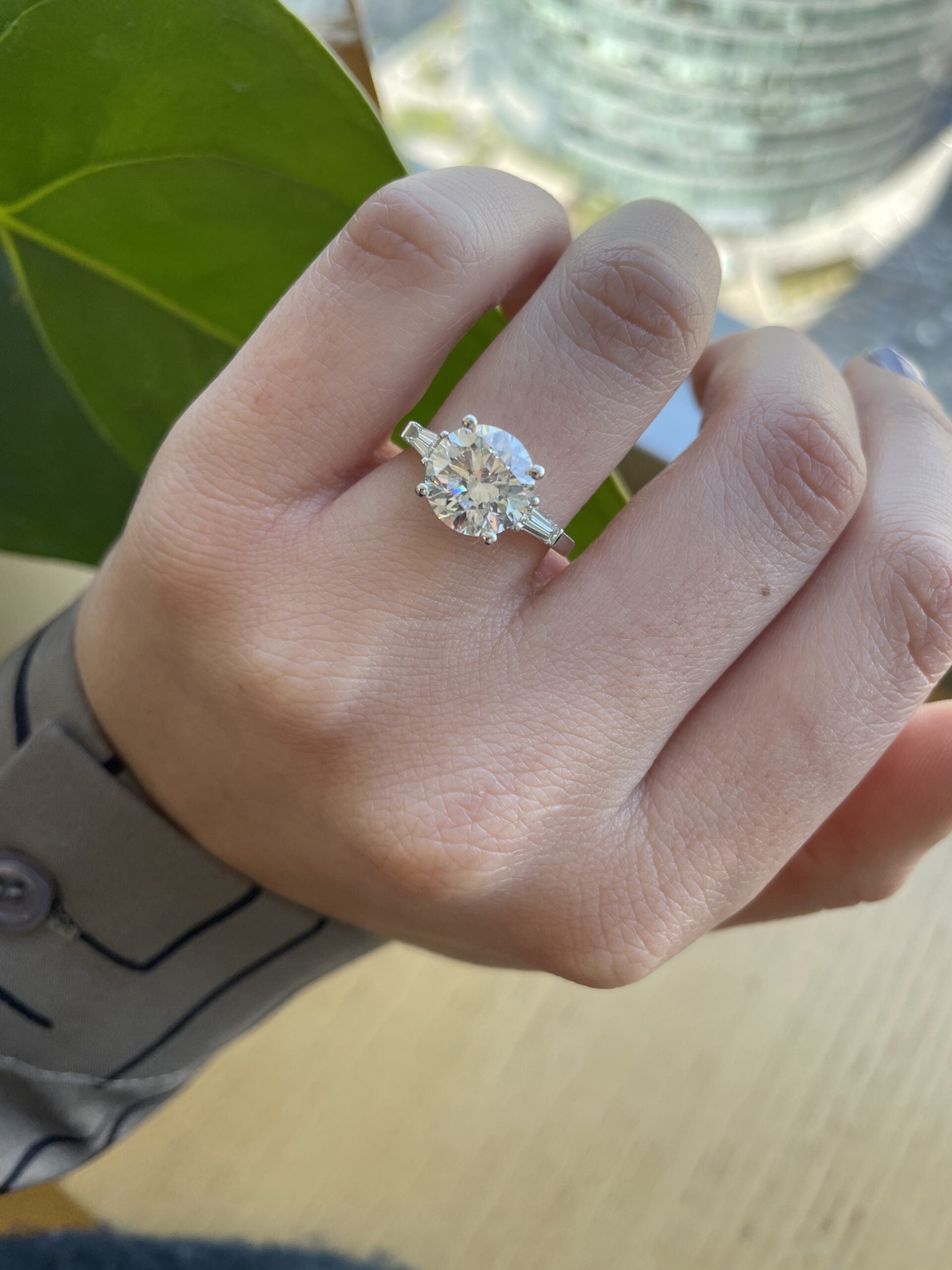 Round cut lab grown diamond three stone engagement ring with prong setting, featuring symbolic trio of diamonds on polished gold band