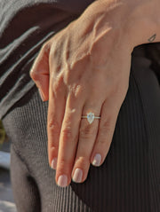 Pear cut lab grown diamond pavé engagement ring with side stones in prong setting on polished gold band