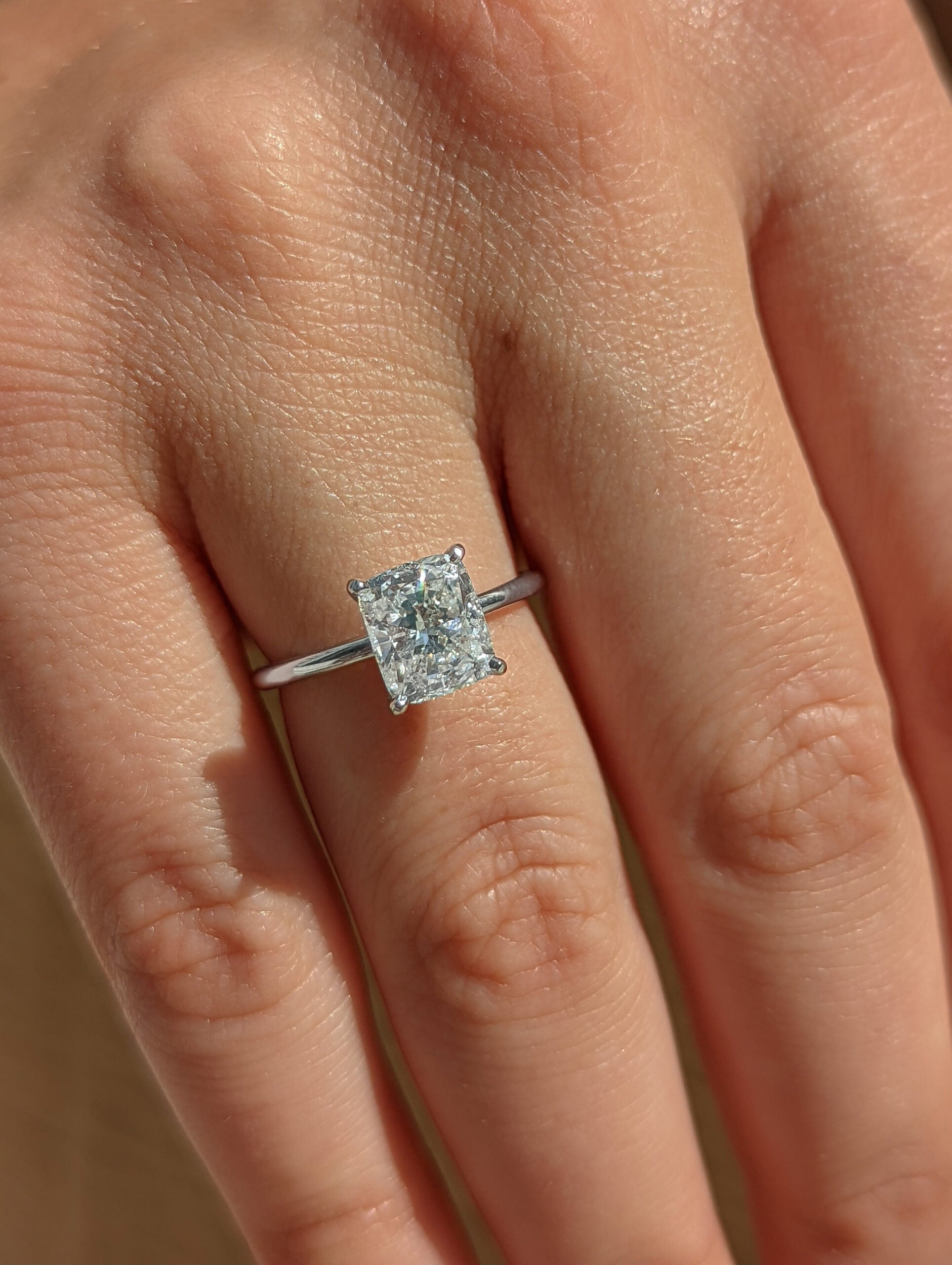 Cushion cut lab grown diamond solitaire engagement ring set in a classic prong setting on polished gold band