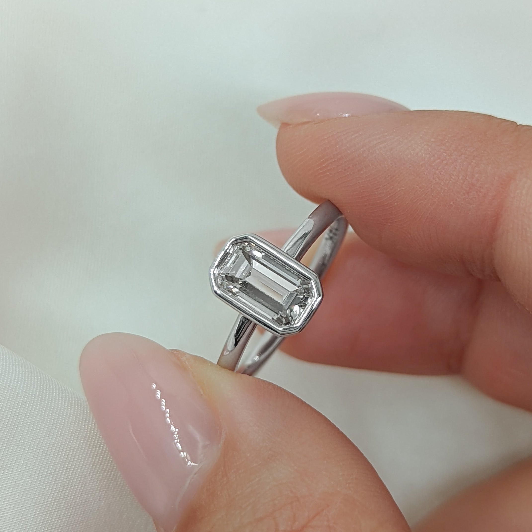 Emerald cut lab grown diamond solitaire engagement ring in classic prong setting on polished gold band
