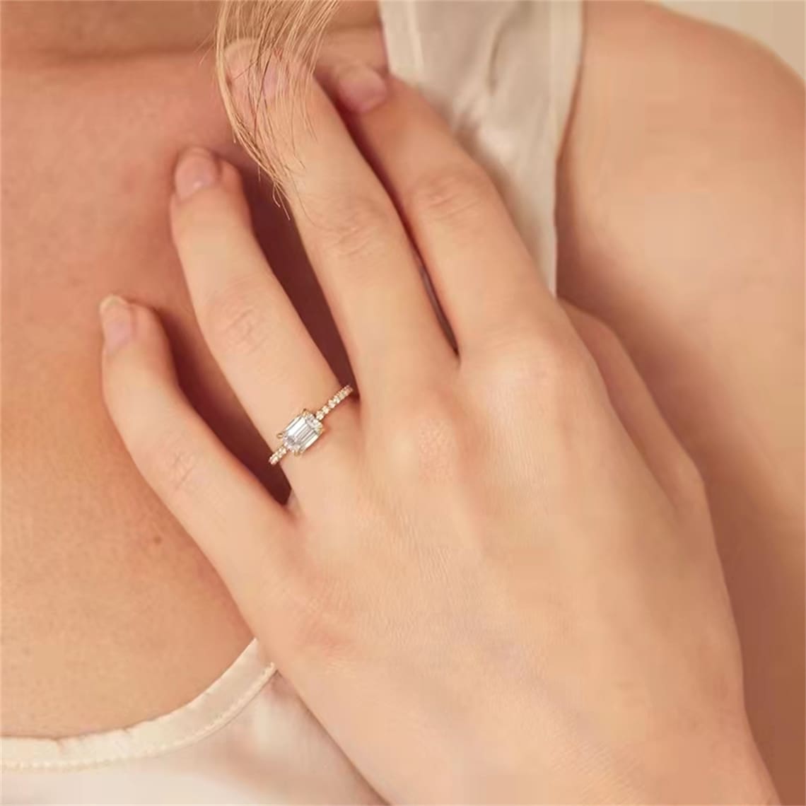 Emerald cut lab grown diamond pavé engagement ring with side stones set in a polished gold band in elegant prong design