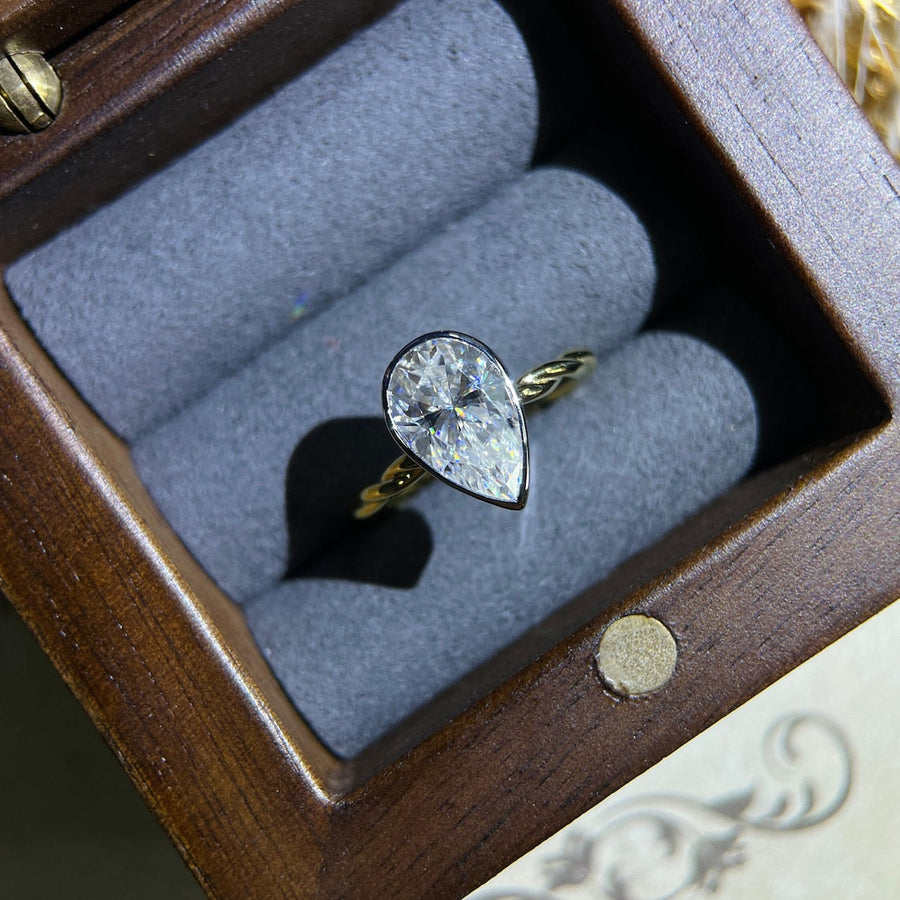 Lab grown diamond engagement ring with pear cut stone in a bezel twisted setting. A unique design that blends modern artistry with timeless romance.