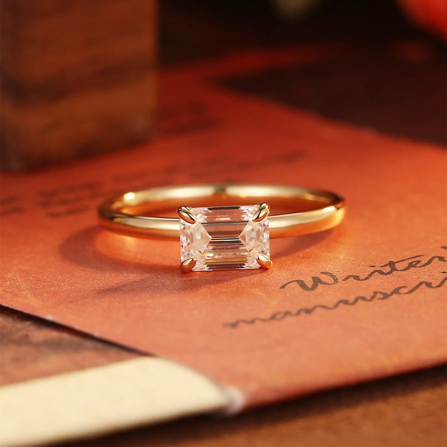 Emerald cut lab grown diamond solitaire engagement ring set in a classic prong design on polished gold band