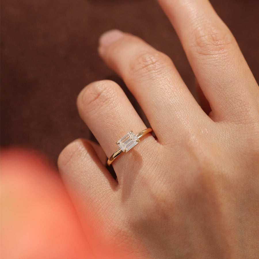 Emerald cut lab grown diamond solitaire engagement ring set in a classic prong design on polished gold band