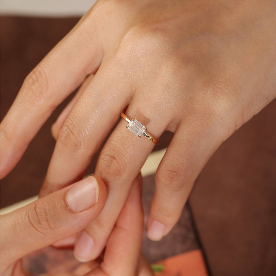 Emerald cut lab grown diamond solitaire engagement ring set in a classic prong design on polished gold band