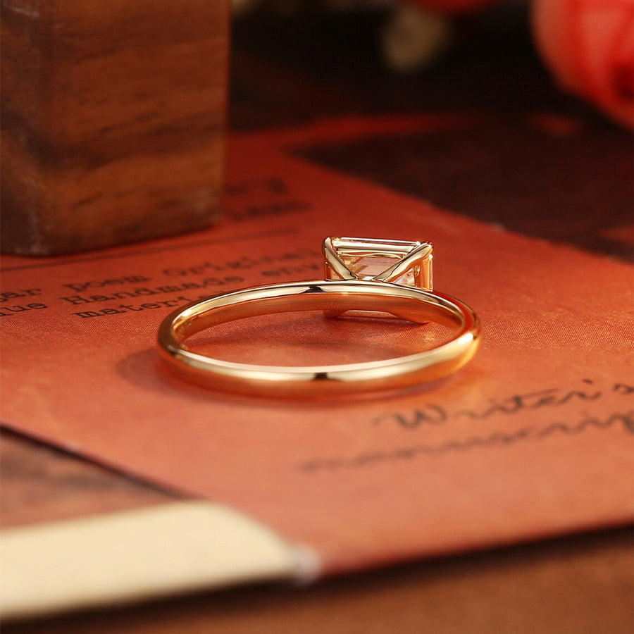 Emerald cut lab grown diamond solitaire engagement ring set in a classic prong design on polished gold band