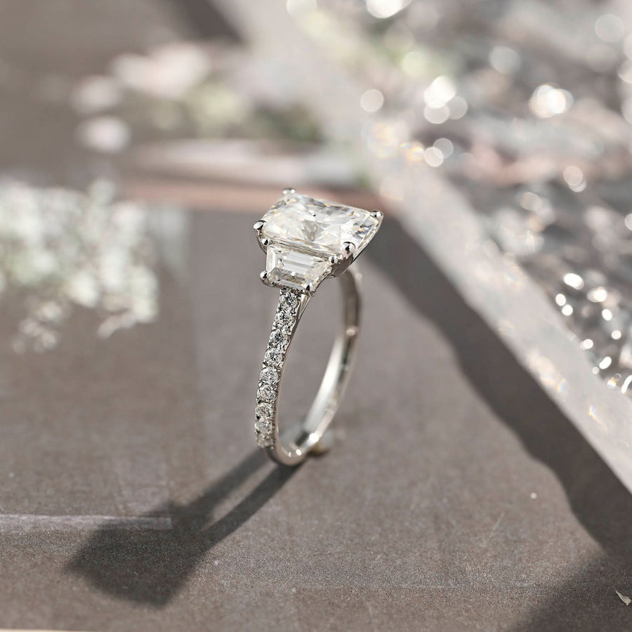 Radiant cut lab grown diamond three stone engagement ring with prong setting on polished gold band