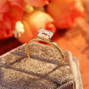 Emerald cut lab grown diamond solitaire engagement ring set in a classic prong design on polished gold band