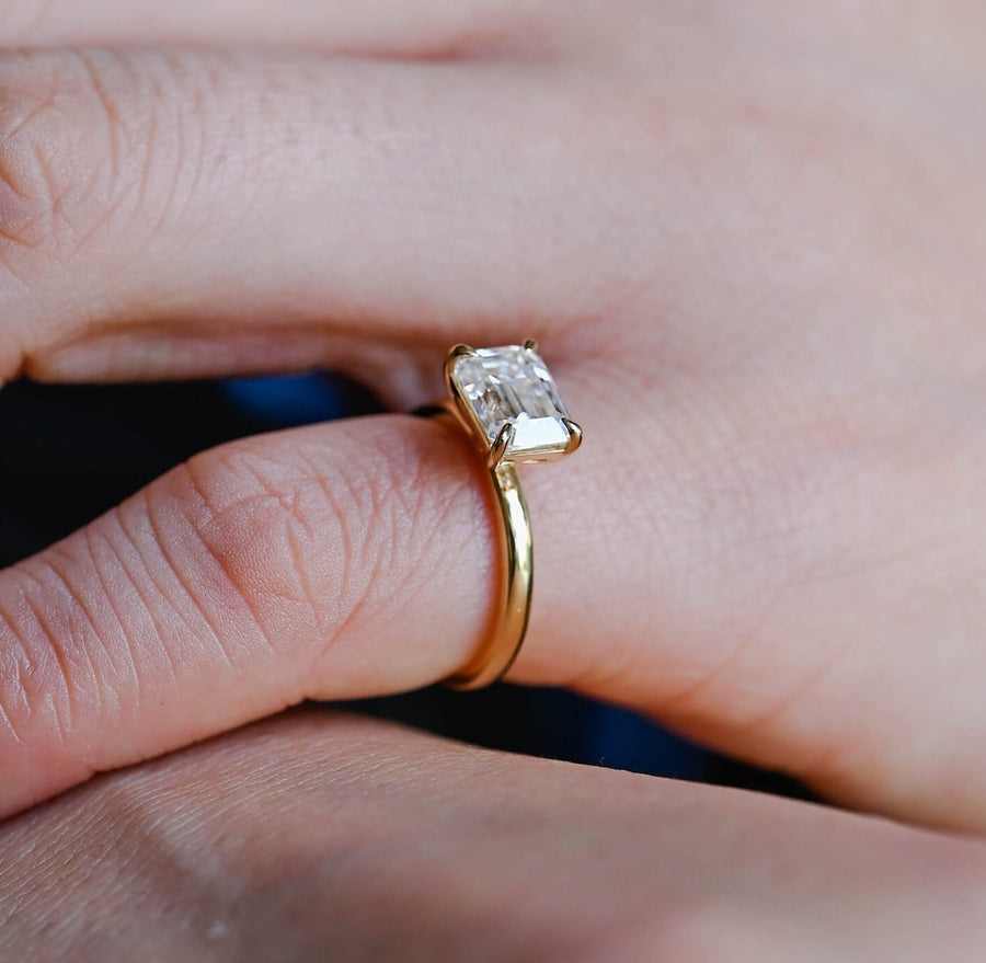 Emerald cut lab grown diamond solitaire engagement ring set in a classic prong design on polished gold band