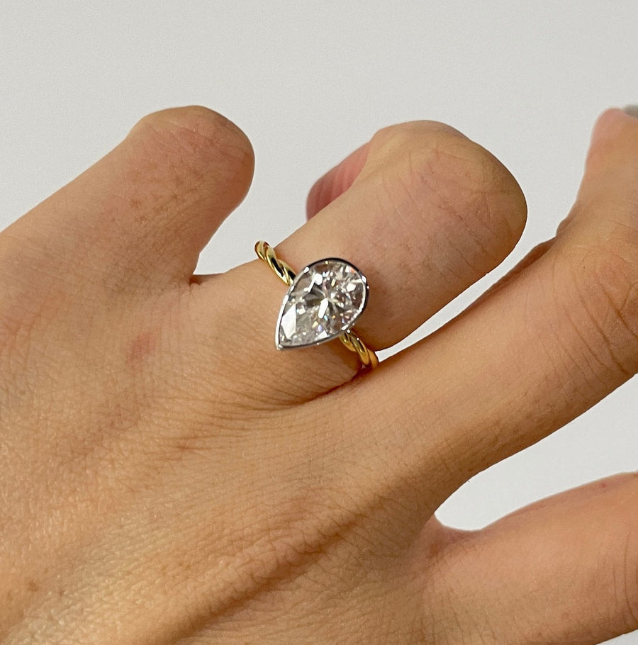 Lab grown diamond engagement ring with pear cut stone in a bezel twisted setting. A unique design that blends modern artistry with timeless romance.