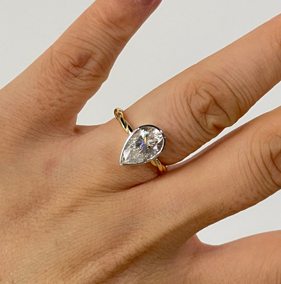 Lab grown diamond engagement ring with pear cut stone in a bezel twisted setting. A unique design that blends modern artistry with timeless romance.