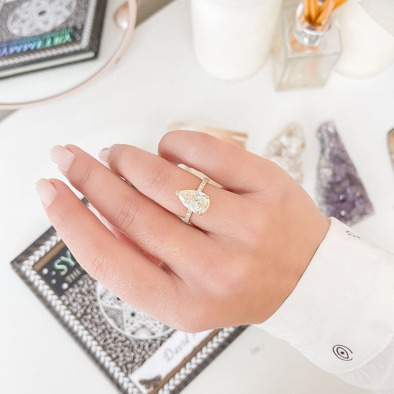 Pear cut lab grown diamond engagement ring with hidden halo and pavé band set in polished gold