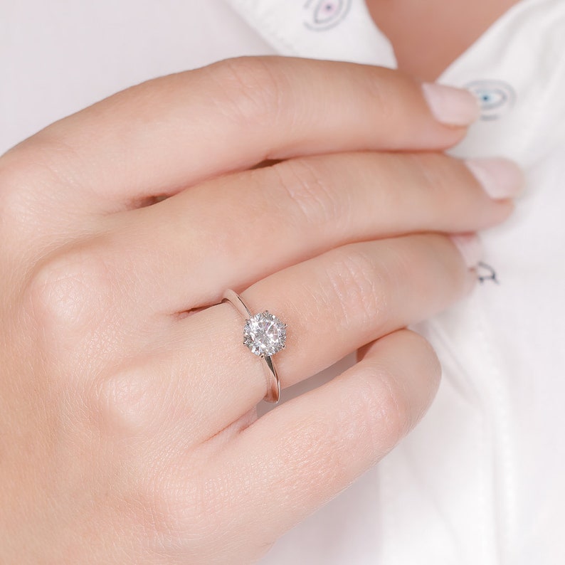 Round cut lab grown diamond solitaire engagement ring in prong setting on polished gold band