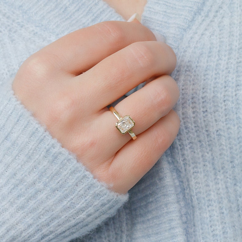 Radiant cut lab grown diamond bezel set engagement ring in polished gold band with minimalist modern design