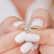 Emerald cut lab grown diamond hidden halo engagement ring with delicate prong setting and polished gold band