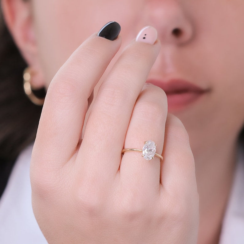 Oval cut lab grown diamond solitaire engagement ring in classic prong setting on polished gold band